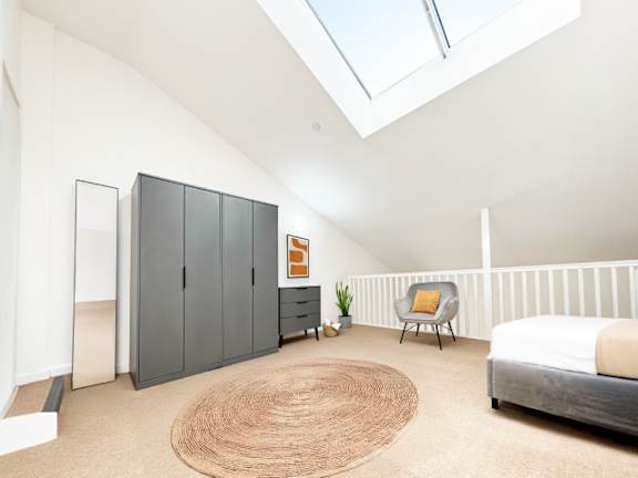 A bedroom with a bed, chair, and cabinet.