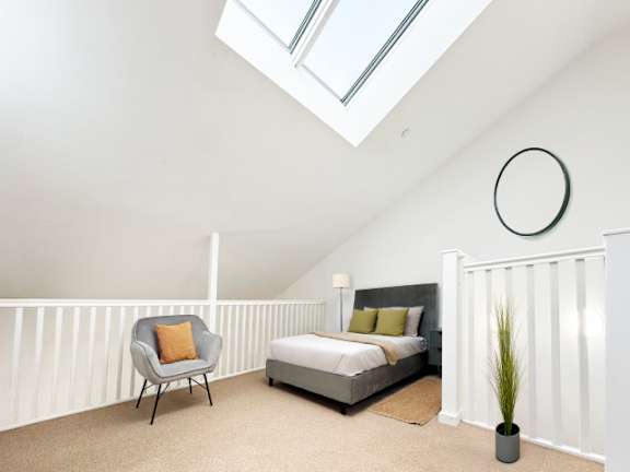 A bedroom with a bed, a chair, and a plant.