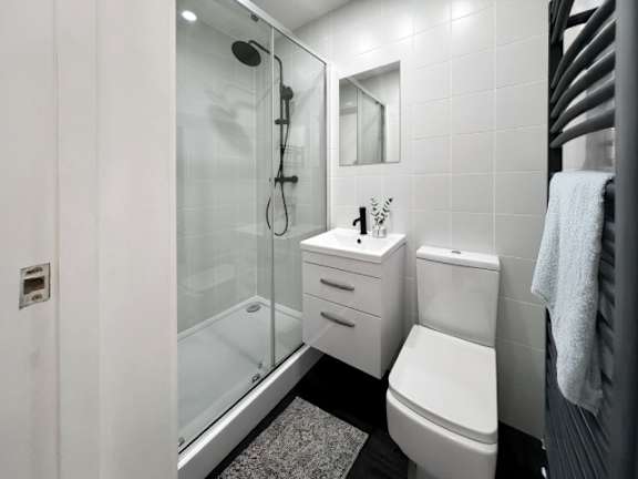 A modern bathroom with a glass shower stall and a white toilet.