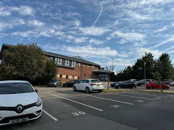 A parking lot with cars and a building in the background.