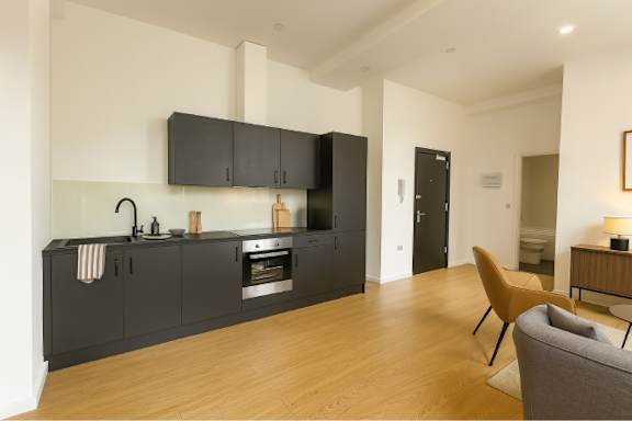 A modern kitchen with wooden floors and black cabinets.