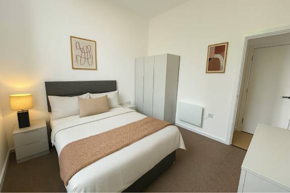 A bedroom with a large bed and a nightstand with a lamp.