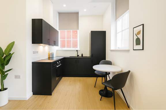 A black chair sits in a kitchen with a white table.