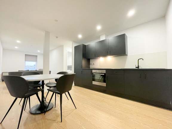 A modern kitchen with black chairs and cabinets.