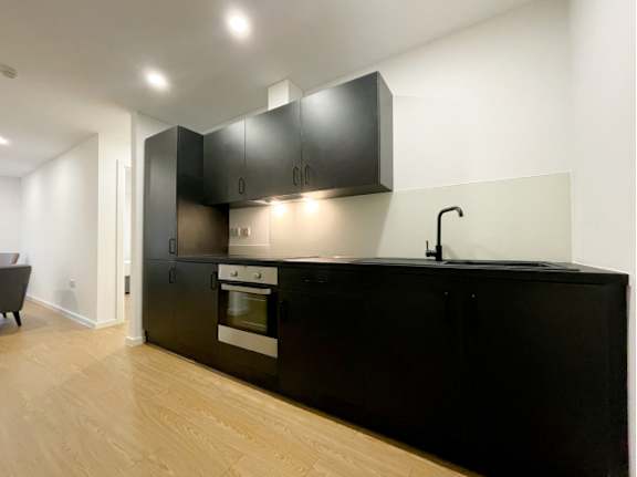 A kitchen with black cabinets and a wooden floor.