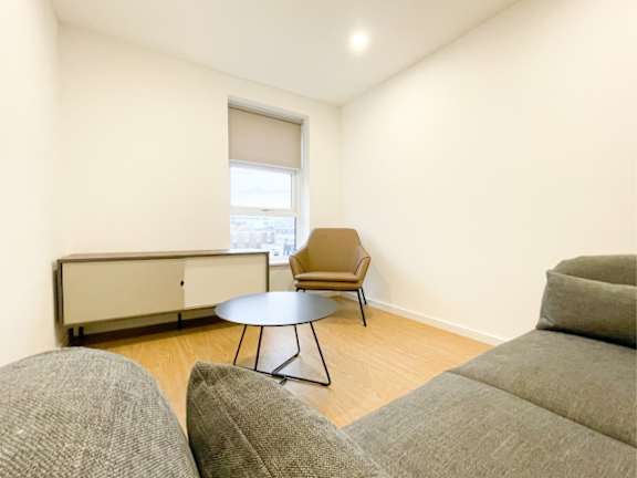 A living room with a grey sofa, a brown chair, and a round table.