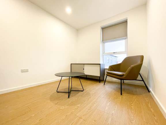 A brown chair sits next to a table in a room with a window.
