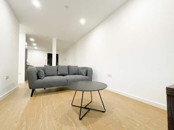 A grey couch with a round table in front of it.
