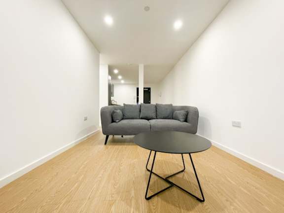 A grey couch sits in a room with a round table in front of it.
