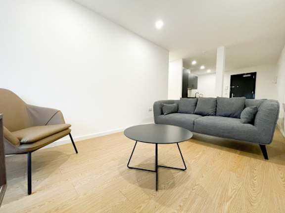 A grey couch sits in a room with a round table in front of it.