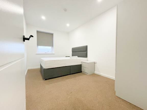 A bedroom with a bed, nightstand, and chair.