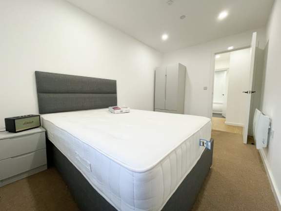 A white bed with a grey headboard and a white mattress in a room.