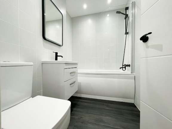 A white bathroom with a toilet, sink, and bathtub.
