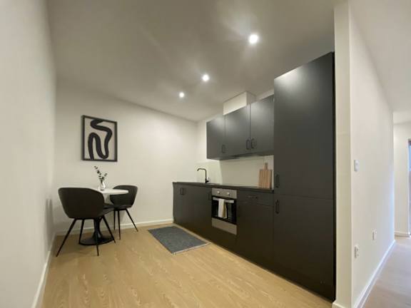 A black kitchen with a table and chairs.