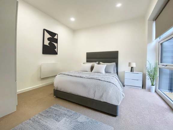 A bedroom with a large bed, a nightstand, and a framed picture on the wall.