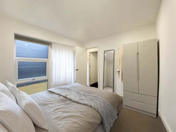 A bedroom with a large bed and a view of the ocean through the window.