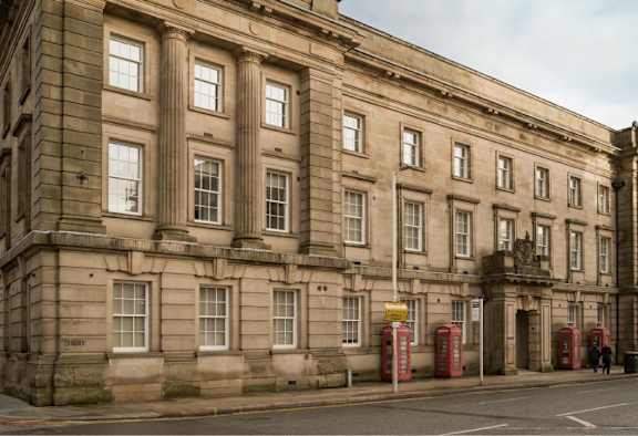 A large, old building with many windows and a yellow sign on the right side.