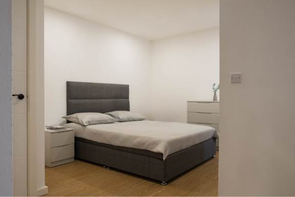 A bedroom with a bed, nightstand, and lamp.