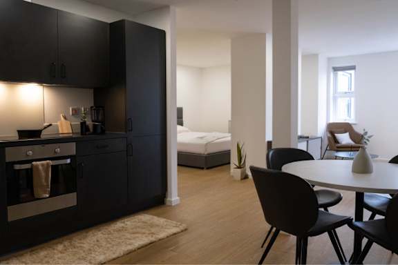 A black kitchen with a table and chairs.