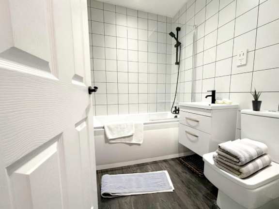 A white bathroom with a white tub, sink, and towel.
