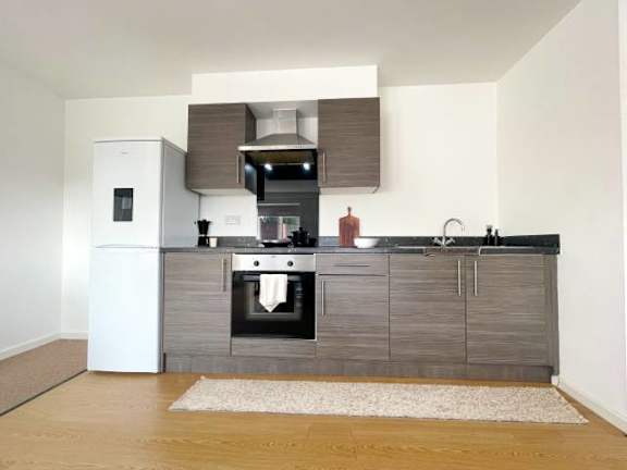 A modern kitchen with a white refrigerator, a black countertop, and wooden cabinets.