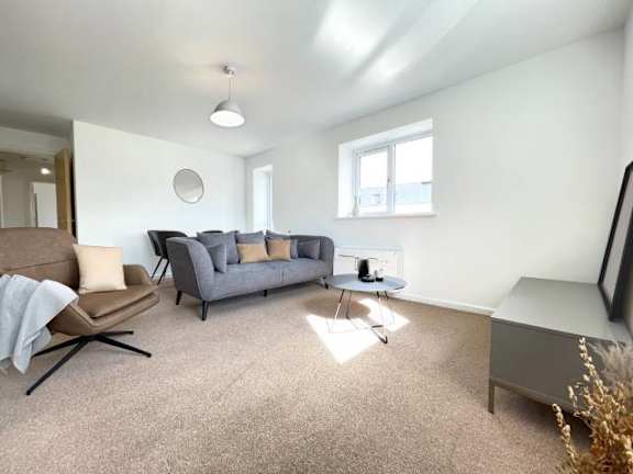 A living room with a grey couch, a brown chair, and a white table.