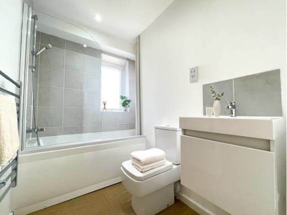 A white toilet sits next to a white sink in a bathroom.