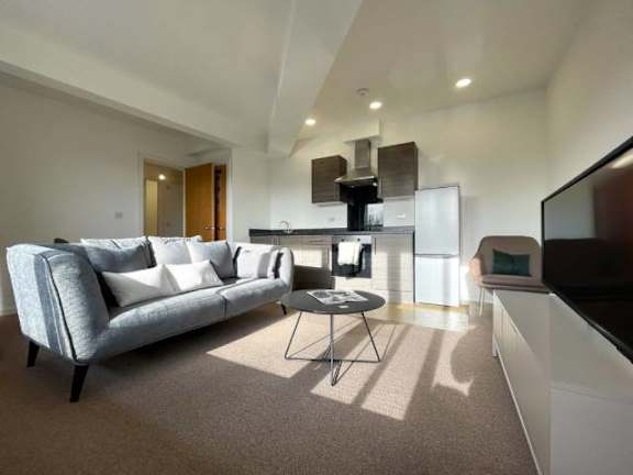 A living room with a grey couch and a black coffee table.