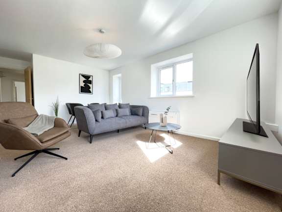 A living room with a grey couch, a chair, and a television.