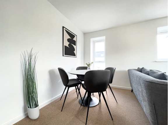 A modern dining room with a white table and black chairs.