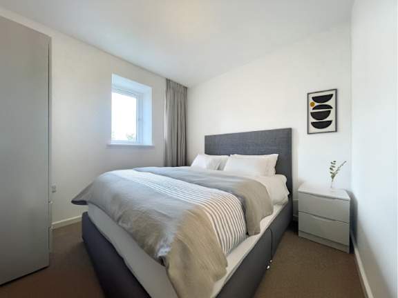 A bedroom with a large bed and a nightstand with a plant on it.