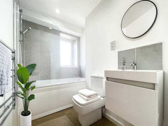 A white bathroom with a toilet, sink, and a plant.