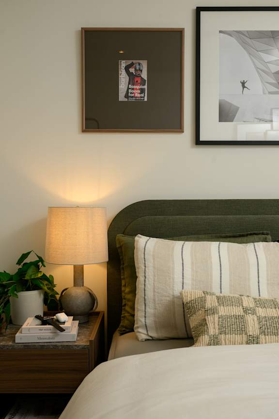 A lamp sits on a nightstand next to a bed.