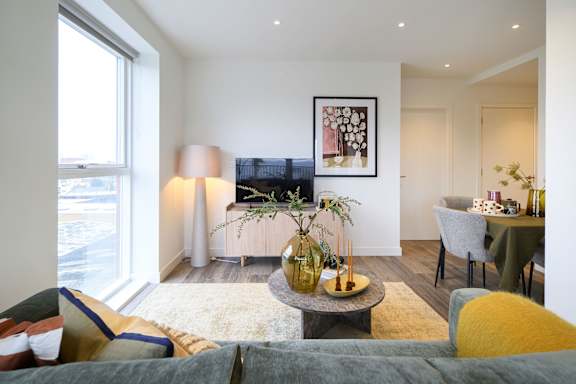 A living room with a grey couch and a coffee table with vases on it.