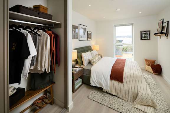 A bedroom with a large bed and a closet full of clothes.