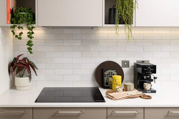A kitchen with a white counter and a black cutting board.
