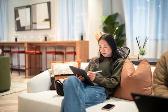 A person is sitting on a couch with a tablet in their lap.