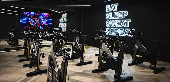 A gym with exercise bikes and a sign that says "Eat Sleep Sweat Repeat".