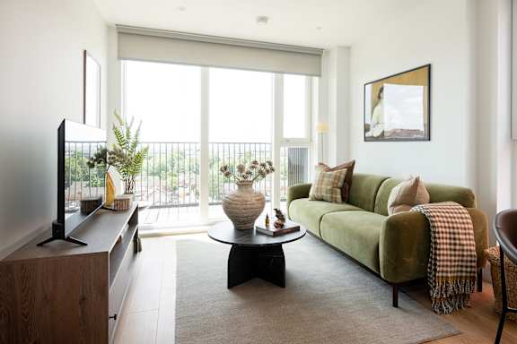 A living room with a green couch and a flat screen TV.