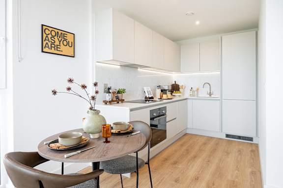 A kitchen with a table and chairs and a sign on the wall.