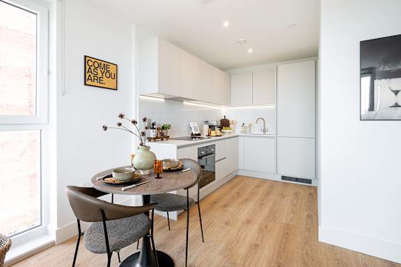 A kitchen with a table and chairs and a sign on the wall.
