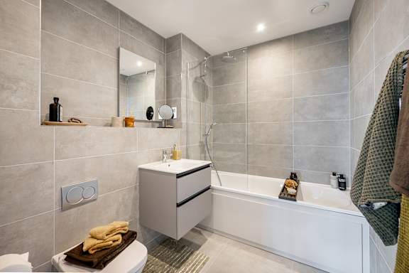 A bathroom with a white tub and a mirror above the sink.