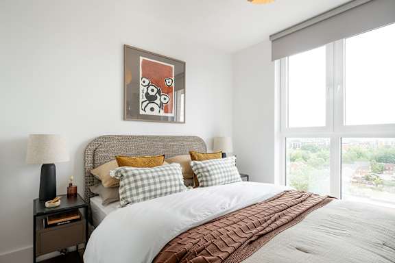 A bedroom with a large bed and a painting on the wall.