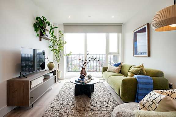 A living room with a green couch and a flat screen TV.