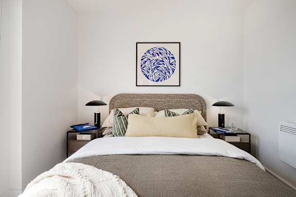 A bedroom with a bed, two lamps, and a framed picture on the wall.