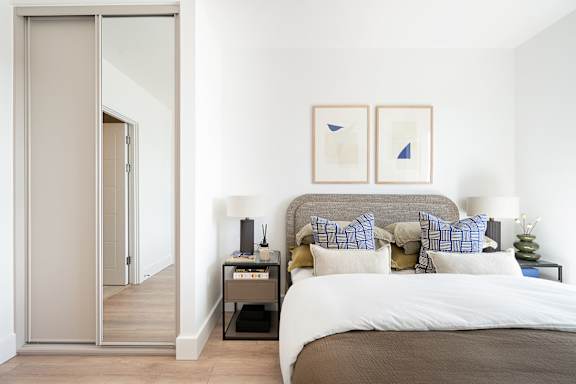 A bedroom with a bed, nightstand, and two framed pictures on the wall.