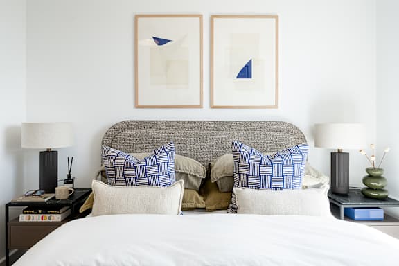 A bed with a white comforter and two blue and white pillows.