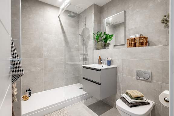 A bathroom with a white toilet, a white bathtub, a mirror, and a plant.