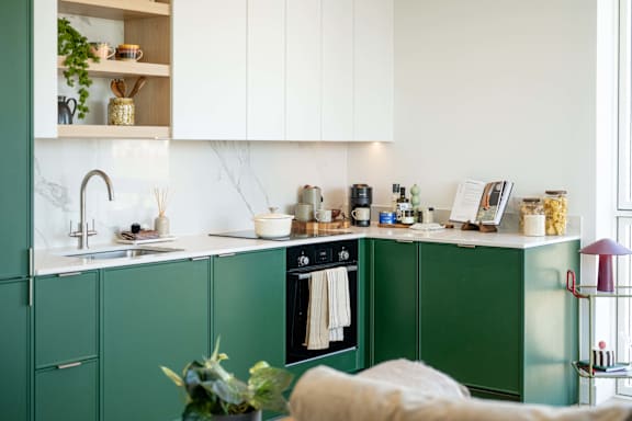 A kitchen with green cabinets and a white countertop.