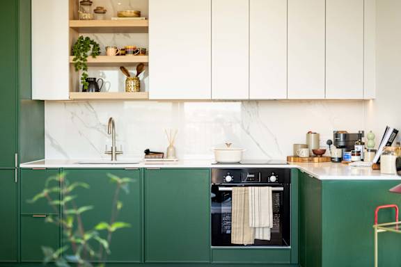 A kitchen with green cabinets and white countertops.